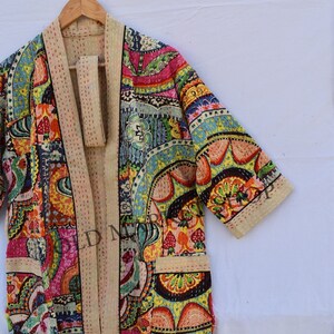 May include: A colorful, patchwork-style kimono robe with a floral and geometric print. The robe has a cream-colored trim and a tie belt.