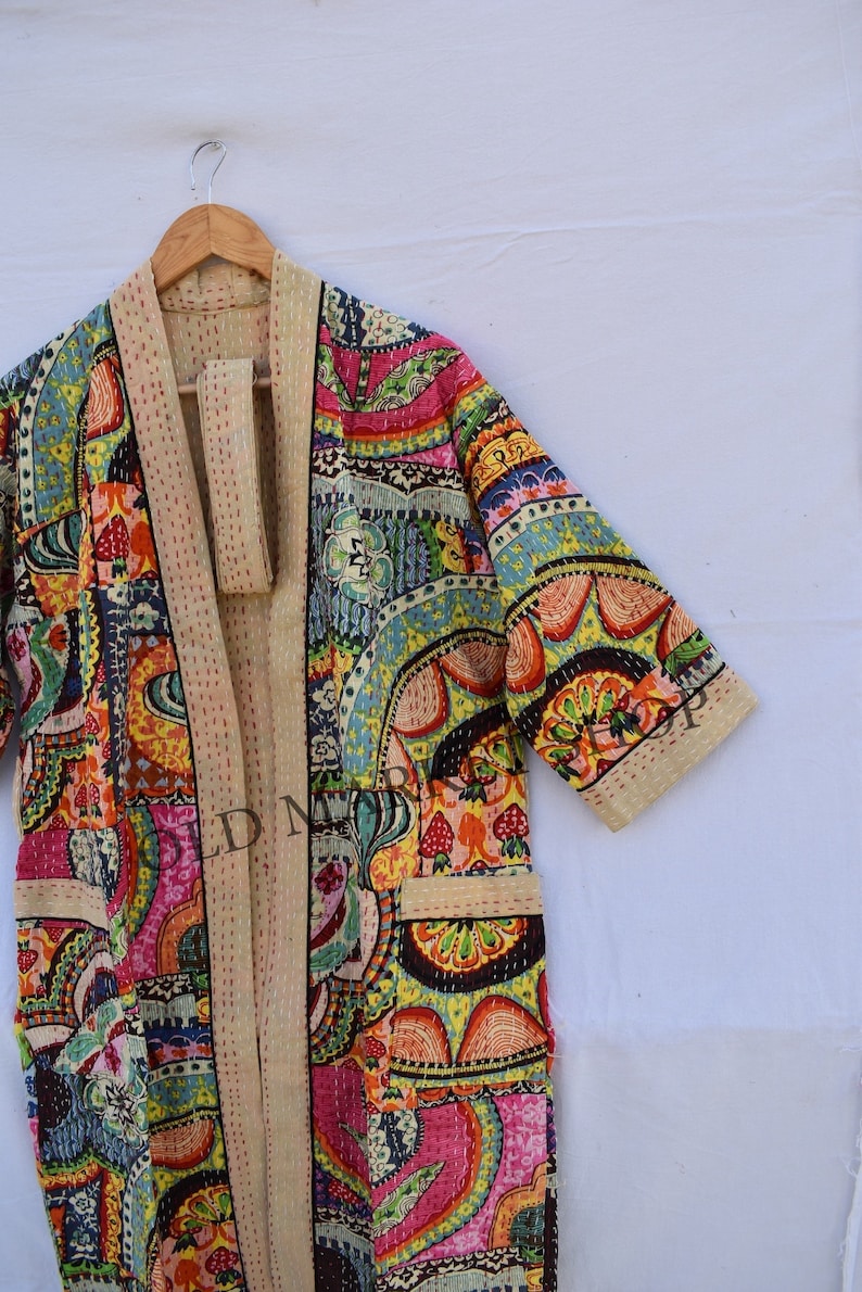 May include: A colorful, patchwork-style kimono robe with a floral and geometric print. The robe has a cream-colored trim and a tie belt.
