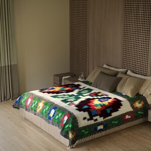 Pu&ograve; includere: Un letto bianco con una coperta colorata a motivi. Il letto &egrave; contro un muro con una testata in pannelli di legno. La coperta ha un design geometrico con colori rosso, verde, blu e giallo.
