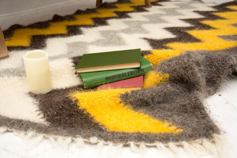 May include: A stack of three books with green, brown, and red covers, resting on a fuzzy, brown and yellow blanket with a zig-zag pattern.