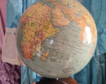 May include: A vintage globe with a wooden stand. The globe is blue and green with a map of the world in yellow, brown, and white. The globe is labeled "Arabisch Mee" and "Indisch O.I."