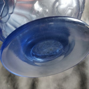 Op de afbeelding: Een blauwe glazen vaas met een mat ontwerp en een heldere blauwe voet. De vaas heeft een ronde, brede voet en een smalle hals.