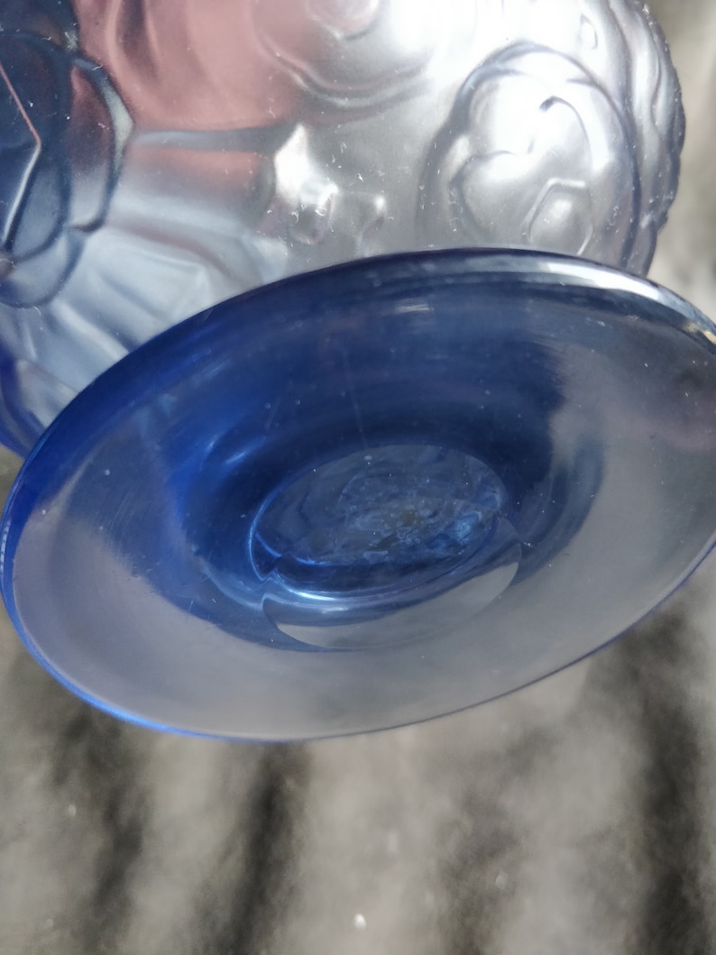 Op de afbeelding: Een blauwe glazen vaas met een mat ontwerp en een heldere blauwe voet. De vaas heeft een ronde, brede voet en een smalle hals.