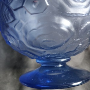 Op de afbeelding: Een blauwe glazen beker met een getextureerd, reli&euml;fdesign. De beker heeft een brede basis en een ronde kom.