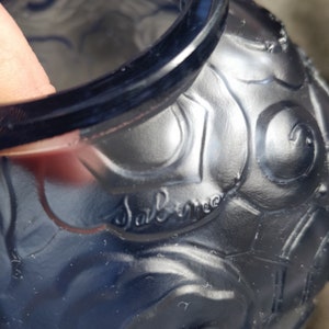 Op de afbeelding: Een blauwe glazen vaas met een getextureerd oppervlak en een reli&euml;fdesign. De vaas heeft een handtekening die "Sabino" aan de zijkant zegt.