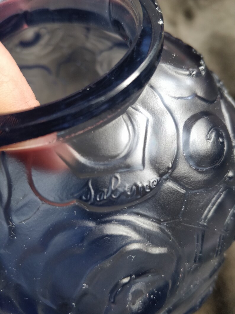 Op de afbeelding: Een blauwe glazen vaas met een getextureerd oppervlak en een reli&euml;fdesign. De vaas heeft een handtekening die "Sabino" aan de zijkant zegt.