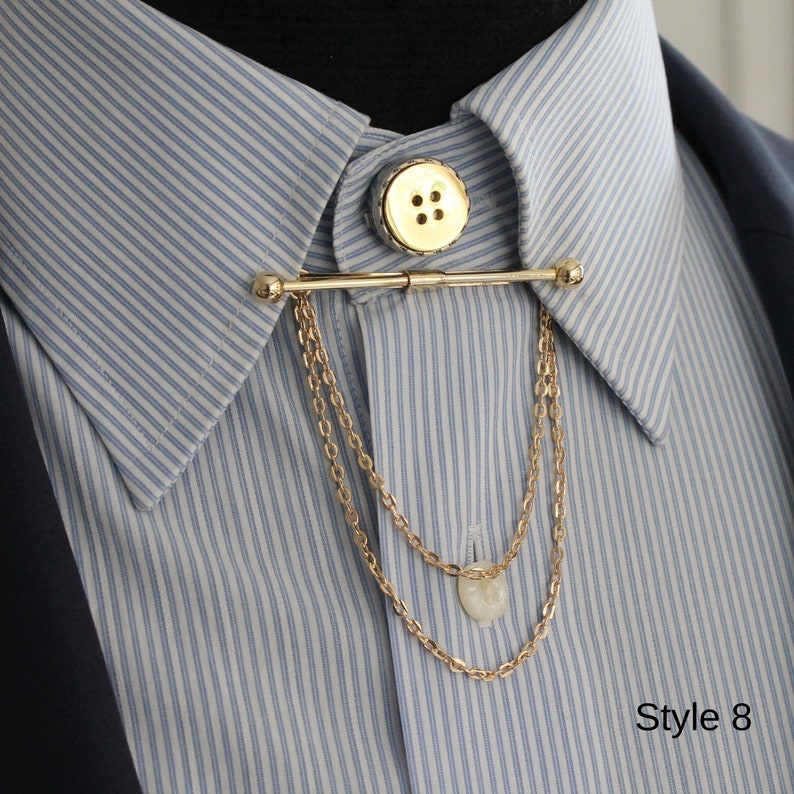 Pode incluir: Uma barra de colarinho dourada com bot&atilde;o e detalhe de corrente, mostrada numa camisa listrada azul e branca. A barra &eacute; presa a um bot&atilde;o na gola e pende com duas correntes delicadas. O texto "Style 8" est&aacute; no canto inferior direito.