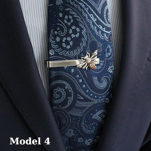 May include: Silver-toned tie clip featuring a detailed bee design with amber-colored accents. The clip is set against a navy blue paisley patterned tie, worn with a navy suit jacket. The text "Model 4" is visible at the bottom.