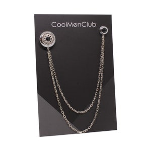 May include: Silver chain with a black stone and a decorative silver button. The chain is displayed on a black card with the text "CoolMenClub".