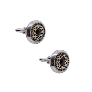 May include: A pair of silver cufflinks with a black stone center and a gold filigree design.