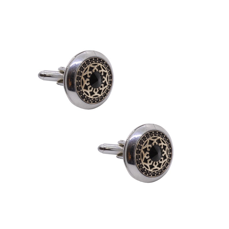 May include: A pair of silver cufflinks with a black stone center and a gold filigree design.