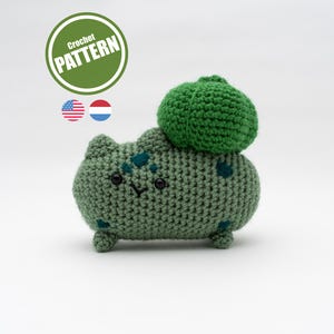 May include: A crocheted green Bulbasaur plushie with a green bulb on its back. The plushie has small black eyes and a stitched smile. A green circle with the words "Crochet Pattern" is in the upper left corner.