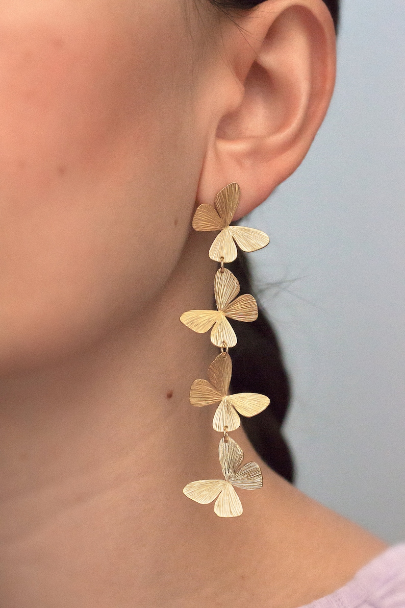 May include: Gold butterfly earrings with five butterflies dangling from each other. The butterflies are textured and have a slightly hammered look.
