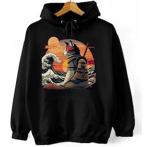 Może przedstawiać: Czarna bluza z kapturem z nadrukiem graficznym przedstawiającym kota w zbroi samurajskiej trzymającego miecz. Kot siedzi na fali z zachodem słońca w tle.