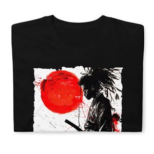 May include: Black t-shirt featuring a graphic design of a samurai with a red sun in the background. The design is in black and white with red accents, creating a striking contrast. The samurai is holding a sword.