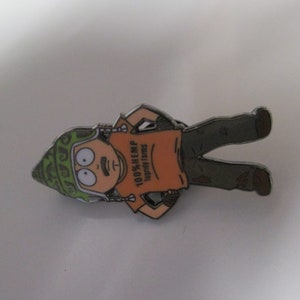 May include: A cartoon character wearing a green helmet and an orange shirt with the text "100% Hemp" and "Legally Famous" printed on it. The character has a mustache and is holding a gun in one hand.