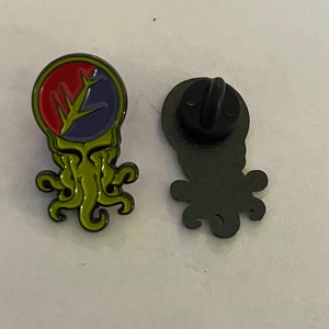 May include: Green, red, and purple enamel pin with a stylized image of a creature with tentacles. The back of the pin is black with a pin back.