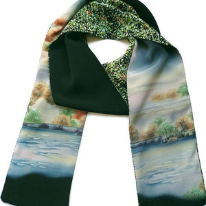 May include: A black and green silk scarf with a watercolor landscape design. The scarf features a lake with trees and a cloudy sky.