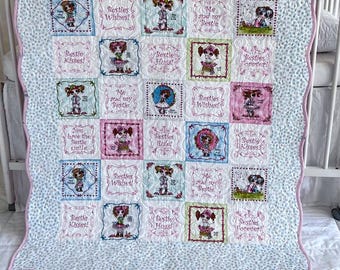May include: A patchwork quilt featuring a repeating pattern of square blocks with embroidered illustrations of children and text including Bestie Wishes, Bestie Kisses, Bestie Hugs, and Me and my Bestie, finished with a light blue and white floral border.