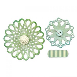 May include: Two green and blue paper doilies with a white pearl button in the center of one and a blue button in the center of the other. A green and yellow striped paper banner is below the doilies.