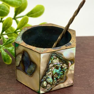 May include: A hexagonal salt cellar made of brass and abalone shell. The cellar has a small spoon inside and iridescent abalone shell accents.