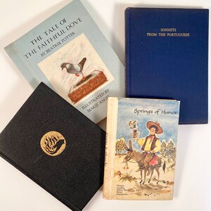May include: A collection of four vintage hardcover books with different titles and authors. The books are arranged in a stack with the top book being a blue book with gold lettering that reads "Sonnets from the Portuguese". The book below it is a light blue book with a picture of a dove on the cover and the title "The Tale of the Faithful Dove" by Beatrix Potter. The book below that is a black book with a gold design of a bird in flames. The bottom book is a white book with a picture of a man riding a donkey and the title "Springs of Humor".