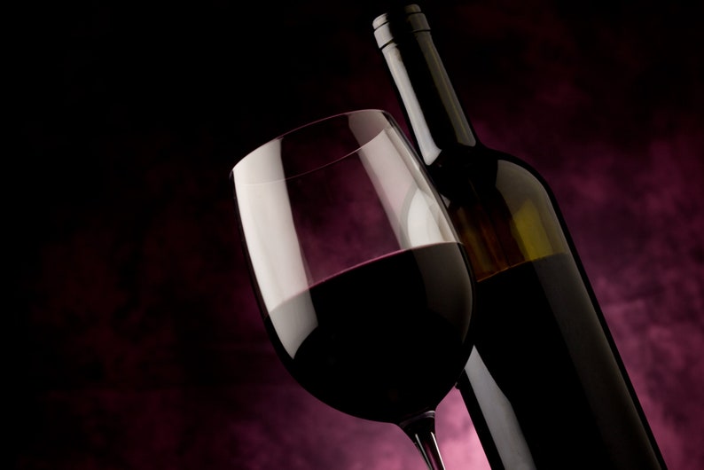 May include: A glass of red wine with a bottle of red wine in the background. The glass is full of wine and the bottle is partially visible.