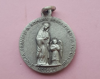 Könnte beinhalten: Ein silberner Anhänger mit einem religiösen Bild einer Frau und eines Kindes. Der Anhänger ist mit den Worten "Sancta Francisca Romana Honopificentia Populi Sui MDCCCLII" beschriftet.