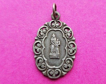 May include: Silver oval pendant with an ornate design. The pendant features a raised image of a woman holding a child.