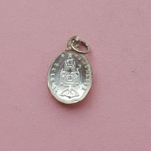 May include: Silver oval pendant with a detailed image of a church and the text "St. James"