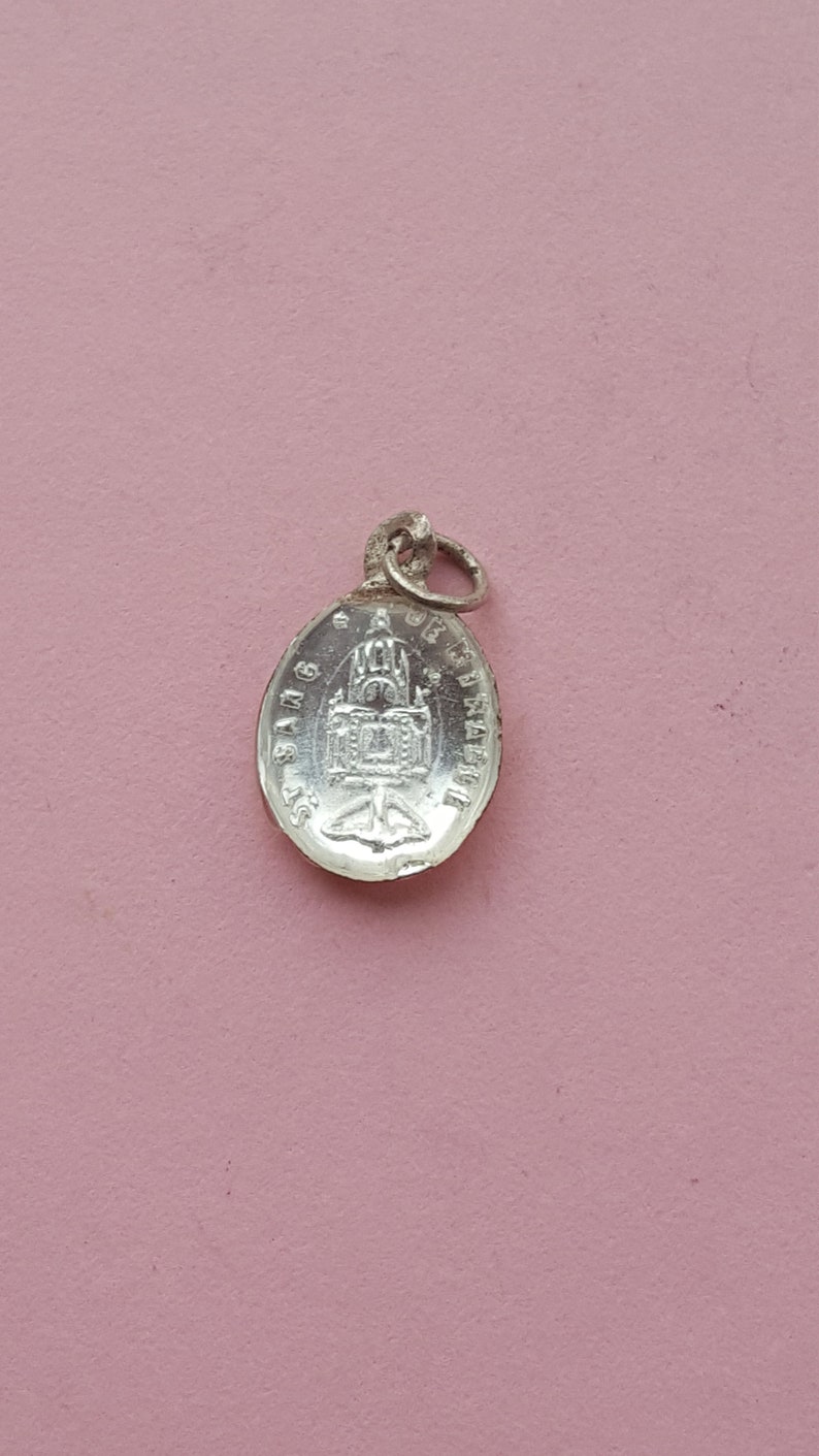 May include: Silver oval pendant with a detailed image of a church and the text "St. James"