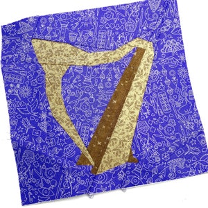 Peut inclure: Un carré de tissu bleu avec un motif blanc de divers objets. Une forme de harpe en tissu brun et beige est superposée au tissu bleu.