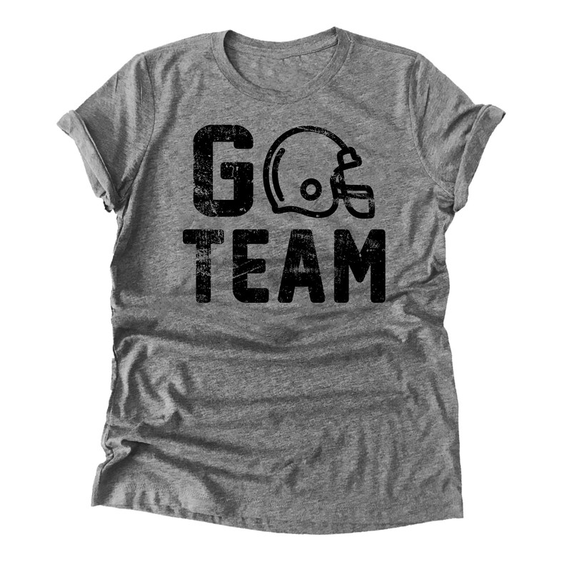 Op de afbeelding: Grijs T-shirt met een zwarte, verweerde afbeelding van een voetbalhelm en de tekst "GO TEAM".