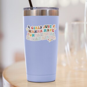 K&ouml;nnte beinhalten: Ein hellblauer Edelstahlbecher mit einem Aufkleber, auf dem "Girls Just Wanna Have Fundamental Human Rights" in bunten Buchstaben mit Sternen und Blitzen steht.