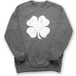 May include: A heather grey sweatshirt with a white distressed four-leaf clover graphic.