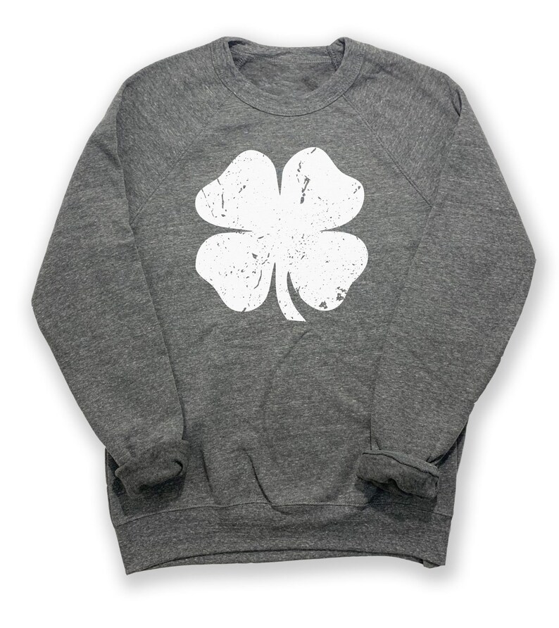 May include: A heather grey sweatshirt with a white distressed four-leaf clover graphic.
