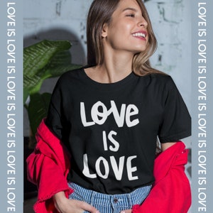 May include: A black t-shirt with the text "Love is Love" printed in white. The shirt is being worn by a person with long brown hair.