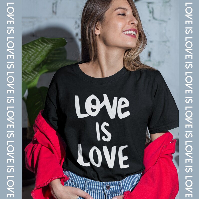 May include: A black t-shirt with the text "Love is Love" printed in white. The shirt is being worn by a person with long brown hair.