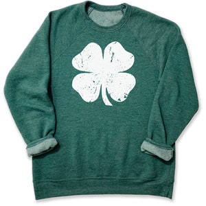 May include: A green sweatshirt with a white distressed four-leaf clover graphic.