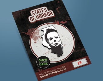 May include: A black and white enamel pin featuring the state of Illinois with the face of Michael Myers from the Halloween franchise. The pin glows in the dark and has the text "States of Horror" and "Glow in the Dark" on the card. The card also has the number "13" on it.