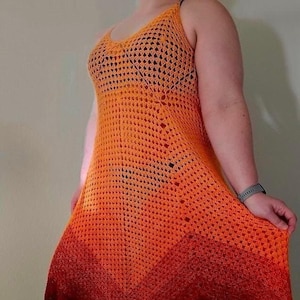Peut inclure: Une longue robe en crochet avec un dégradé d'orange, de rouge et de noir. La robe a une coupe ample et fluide et est sans manches.