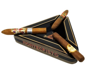 May include: A black triangular ashtray with gold accents and the words "Montecristo" printed on the front. Three cigars are resting in the ashtray.
