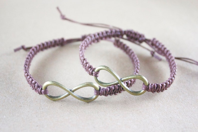 May include: Two matching bracelets with a woven, mauve-colored band and a bronze-colored infinity symbol. The bracelets are adjustable with a sliding knot closure. The bracelets are a symbol of everlasting love and friendship.
