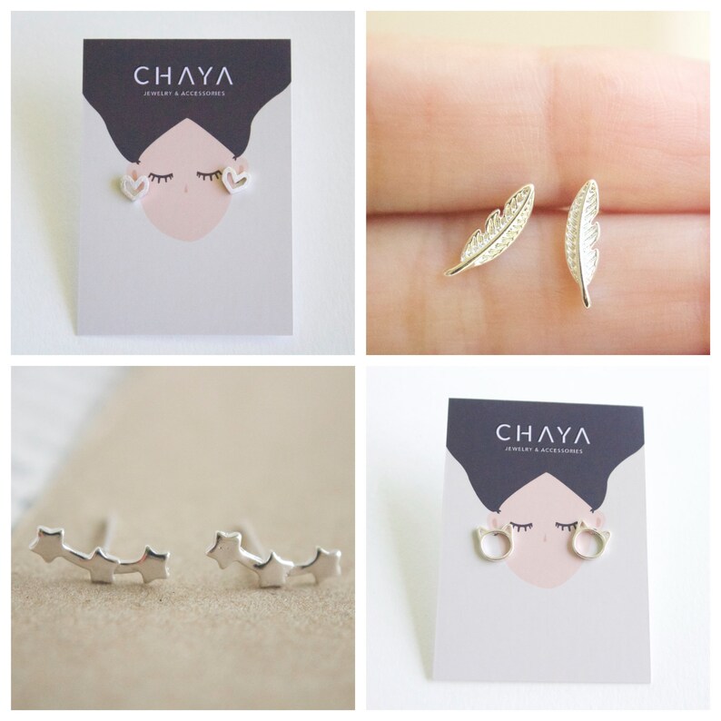 May include: Four pairs of silver earrings displayed on white cards with the text "CHAYA Jewelry & Accessories". The earrings are in the shapes of hearts, feathers, stars, and cats.