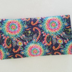 May include: A long, rectangular wallet with a dark blue background and a colorful paisley pattern. The pattern features bright pink, yellow, green, and blue colors.