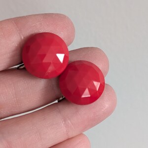 May include: A pair of red clip-on earrings with a faceted design.
