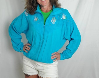 May include: A turquoise blue jacket with a zipper closure and a white background. The jacket has a seahorse and fish design embroidered on the front.