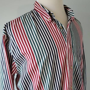 Puede incluir: Una camisa de manga larga con botones y rayas diagonales en rojo, verde, azul marino y blanco.