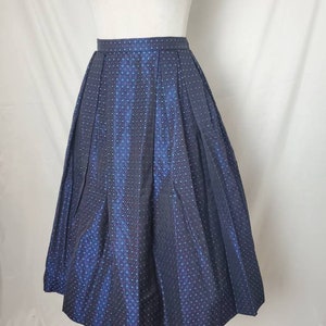 May include: A navy blue skirt with a subtle polka dot pattern. The skirt is pleated and has a full, A-line silhouette.