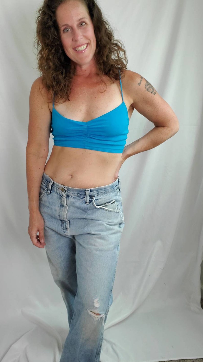K&ouml;nnte beinhalten: Eine Frau tr&auml;gt ein hellblaues Crop-Top und eine hellblaue Jeans mit einem ausgefransten Knie.